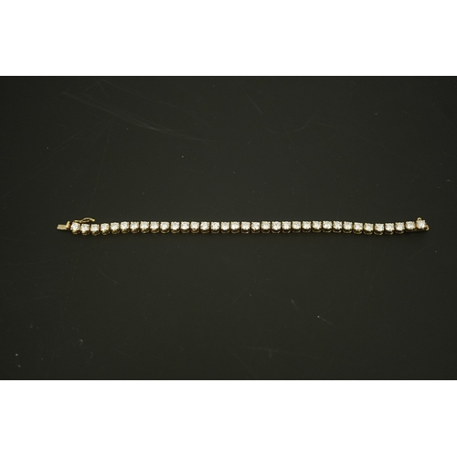 268 - A modern 14k gold and thirty five stone round brilliant cut diamond set tennis bracelet, each stone ... 