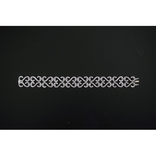 280 - A modern 18k white gold and diamond chip cluster set bracelet, with shaped scroll links, 17cm, gross... 