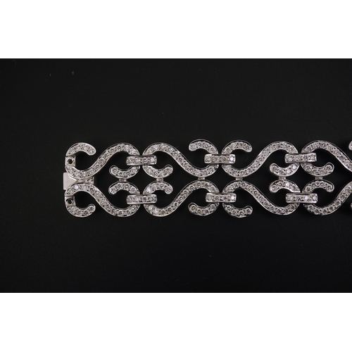 280 - A modern 18k white gold and diamond chip cluster set bracelet, with shaped scroll links, 17cm, gross... 