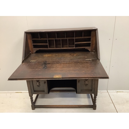 1031 - A dark oak Tudor style bureau with a decorative carved front, single drawer above cupboard doors, wi... 