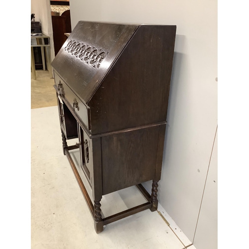 1031 - A dark oak Tudor style bureau with a decorative carved front, single drawer above cupboard doors, wi... 