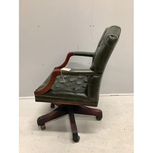 1084 - A reproduction mahogany and buttoned green leather swivel desk chair, width 56cm, depth 50cm, height... 