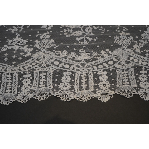 1546 - A deep elaborately designed flounce of mid 19th century Brussels bobbin appliquéd lace on net, with ... 