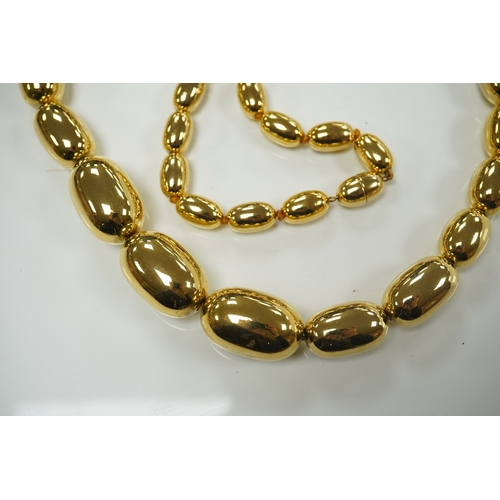 1950 - A modern gilt metal graduated oval bead costume necklace, 72cm. Condition - fair to good