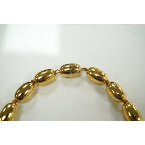 1950 - A modern gilt metal graduated oval bead costume necklace, 72cm. Condition - fair to good