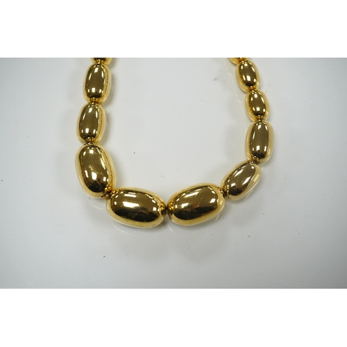 1950 - A modern gilt metal graduated oval bead costume necklace, 72cm. Condition - fair to good