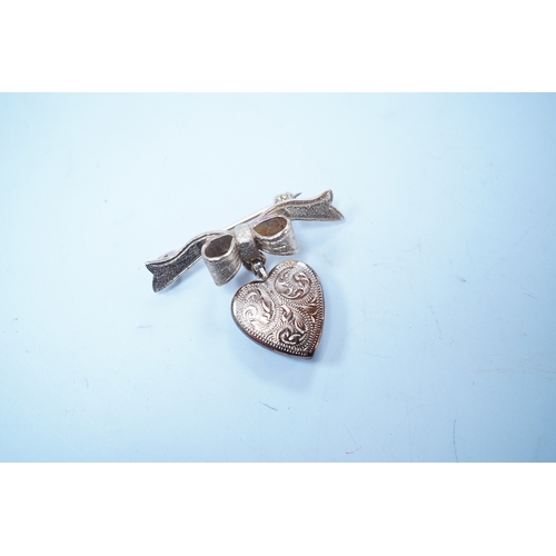 1955 - A modern engraved 9ct gold heart shaped locket, on an associated 9ct gold ribbon bow suspension broo... 