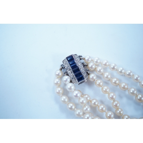 1963 - A triple strand cultured pearl choker necklace, with sapphire and diamond cluster set rectangular wh... 