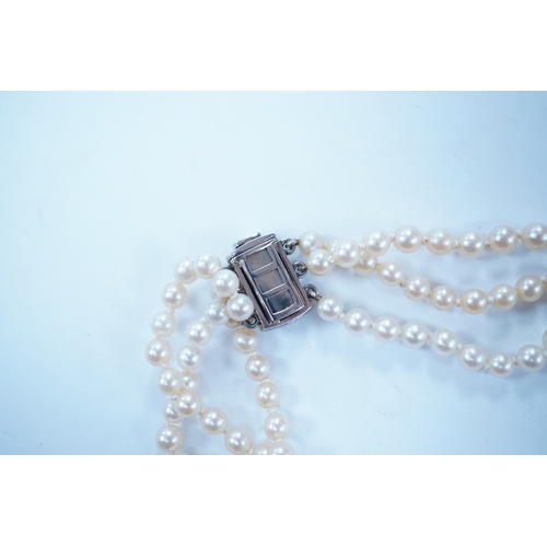 1963 - A triple strand cultured pearl choker necklace, with sapphire and diamond cluster set rectangular wh... 