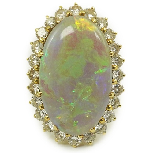 1966 - An 18ct  gold, white opal and diamond set oval cluster dress ring, the cabochon opal measuring appro... 