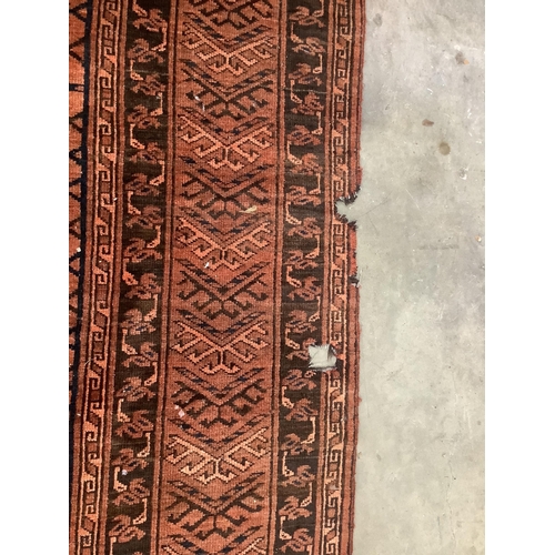 37 - An Afghan rust ground carpet, 400 x 260cm. Condition - poor, damage to border