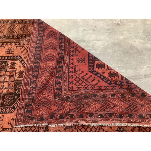 37 - An Afghan rust ground carpet, 400 x 260cm. Condition - poor, damage to border