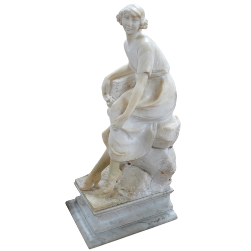 519 - A French 1920s-30s alabaster sculpture of a lady seated on a stone wall, sculpture mounted on a ma... 