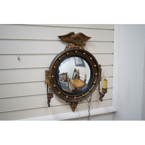 603 - A circular convex gilt girandole mirror with carved eagle surmount, 62cm high. Condition - wing tip ... 