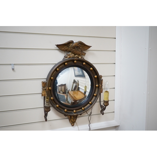 603 - A circular convex gilt girandole mirror with carved eagle surmount, 62cm high. Condition - wing tip ... 