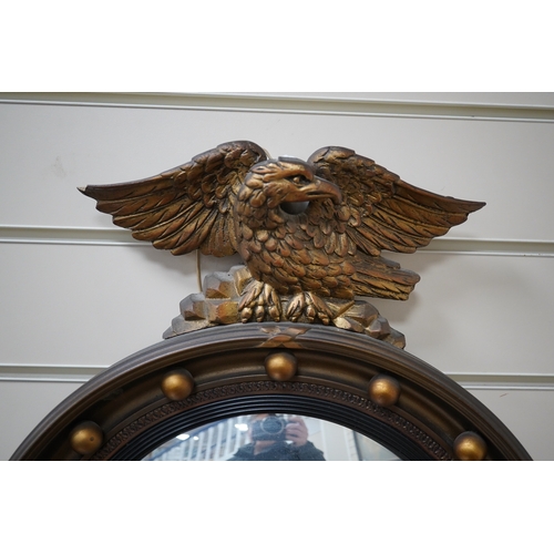 603 - A circular convex gilt girandole mirror with carved eagle surmount, 62cm high. Condition - wing tip ... 