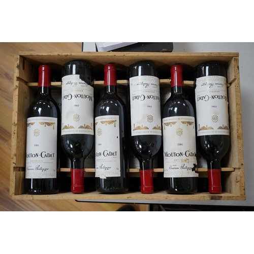 608 - Twelve bottles of Mouton Cadet 1986 in associated wooden crate. Condition - wear to labels, storage ... 