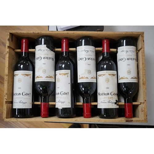 608 - Twelve bottles of Mouton Cadet 1986 in associated wooden crate. Condition - wear to labels, storage ... 