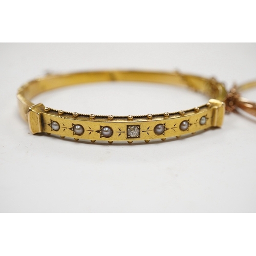 933 - An Edwardian yellow metal, diamond and seed pearl set hinged bangle and one other late Victorian eng... 