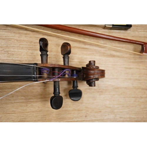 1288 - A late 19th century German violin, body 35cm long, and two bows. Condition - poor to fair.