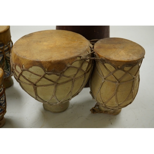 1293 - Five African drums; a Djembe, 60cm high, together with four small North African pottery double drums... 