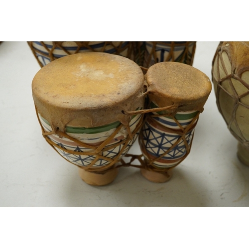 1293 - Five African drums; a Djembe, 60cm high, together with four small North African pottery double drums... 