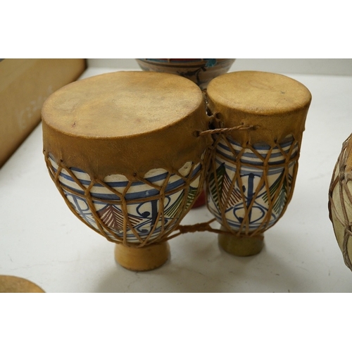 1293 - Five African drums; a Djembe, 60cm high, together with four small North African pottery double drums... 