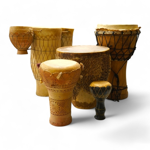 1294 - Five African drums; a Djembe, 50cm high, together with four others, including a pottery triple drum,... 