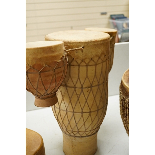 1294 - Five African drums; a Djembe, 50cm high, together with four others, including a pottery triple drum,... 