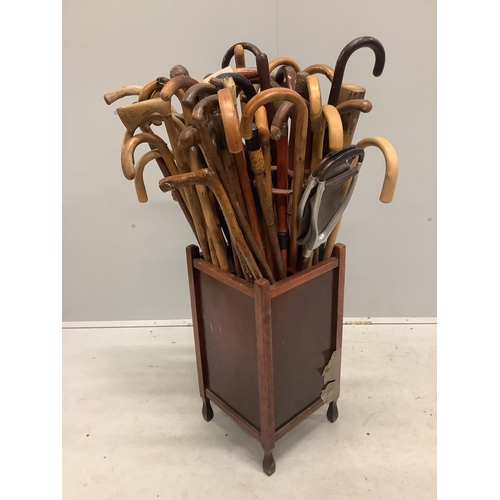 31 - A large collection of assorted walking and shooting sticks in four division stick stand. Condition -... 