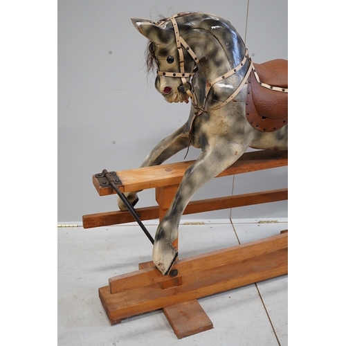 340 - An early 20th century dapple grey rocking horse, on later trestle base, length 132cm. Condition - fa... 