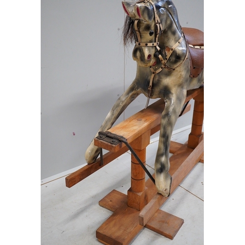 340 - An early 20th century dapple grey rocking horse, on later trestle base, length 132cm. Condition - fa... 