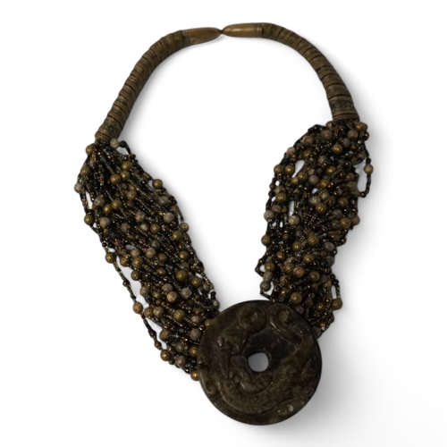 528 - A Chinese multi bead necklace with carved bowenite dragon pendant, disc 6cm in diameter. Condition... 