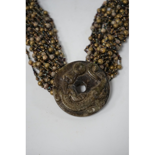 528 - A Chinese multi bead necklace with carved bowenite dragon pendant, disc 6cm in diameter. Condition... 