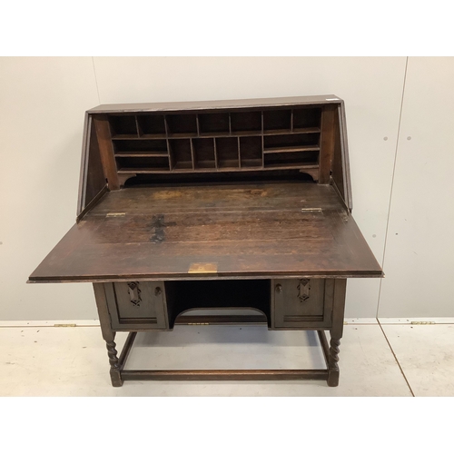 1107 - A dark oak Tudor style bureau with a decorative carved front, single drawer above cupboard doors, wi... 