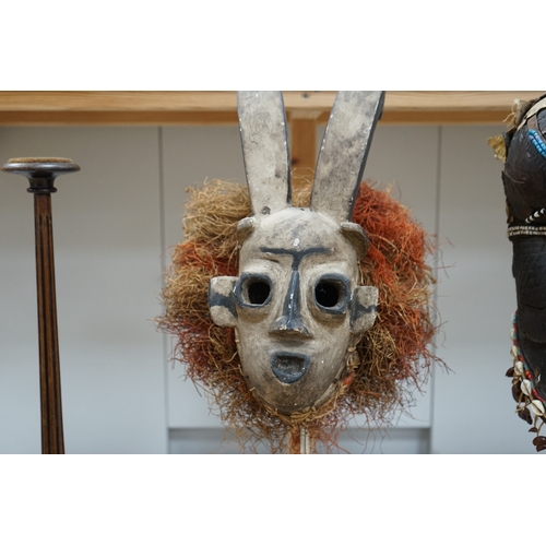 1310 - An African Kuba helmet mask and another horned mask, both on stands & one spare. Condition - helmet ... 