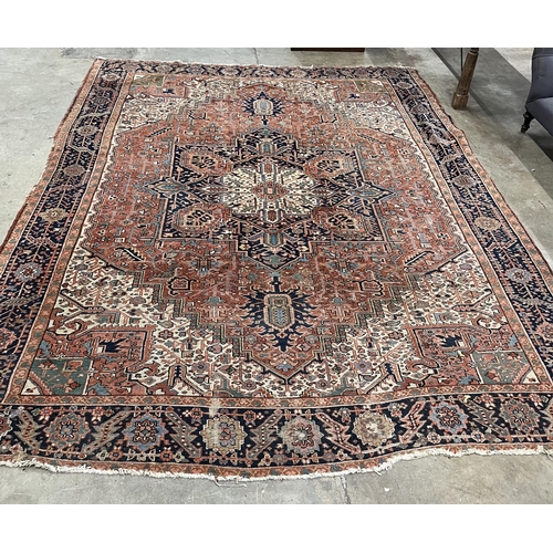 117 - An antique Heriz brick red ground carpet, 350 x 274cm. Condition - fair