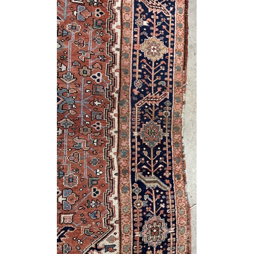 117 - An antique Heriz brick red ground carpet, 350 x 274cm. Condition - fair