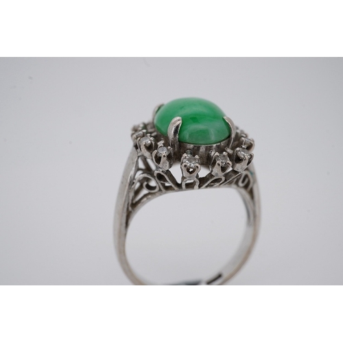 1928 - A white metal and cabochon jade set ring, with round cut diamond set border, size N, gross weight 5.... 