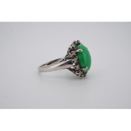 1928 - A white metal and cabochon jade set ring, with round cut diamond set border, size N, gross weight 5.... 