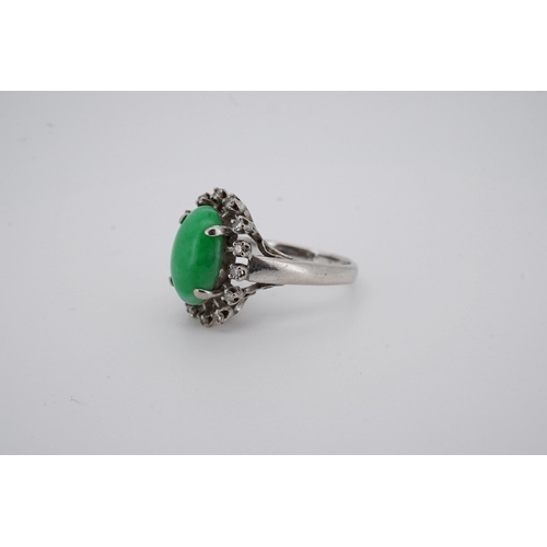 1928 - A white metal and cabochon jade set ring, with round cut diamond set border, size N, gross weight 5.... 