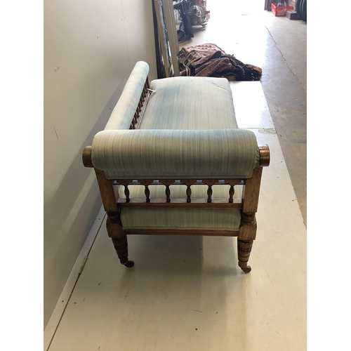 44 - An Edwardian oak chaise longue, upholstered in green cord, on turned and carved legs fitted castors,... 