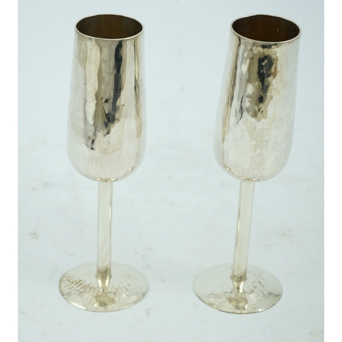 104 - A pair of Elizabeth II planished silver champagne flutes, by Pruden & Smith, on planished domed foot... 