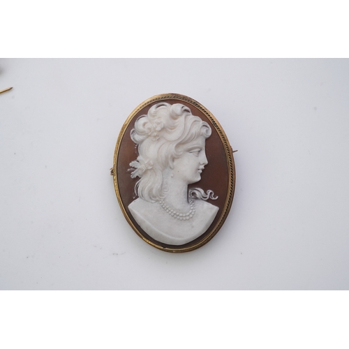 188 - Three shell cameo brooches, 20th century comprising: one depicting a young girl holding a baby goat ... 