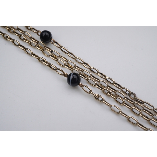 204 - An elegant onyx longchain necklace, early 20th century, composed of elongated belcher linking in gol... 