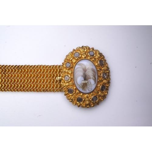 212 - A fine sentimental Georgian gold and hairwork bracelet, 1820s, the oval clasp centring on a glazed c... 