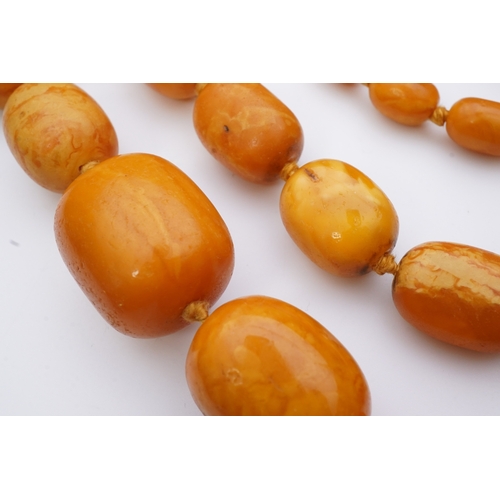 234 - A single strand graduated oval amber bead necklace, length 104cm, gross weight 163 grams