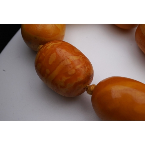 234 - A single strand graduated oval amber bead necklace, length 104cm, gross weight 163 grams