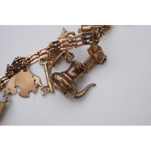 243 - A charm bracelet, mid 20th century, the 9ct gate link bracelet suspending a series of twelve charms ... 