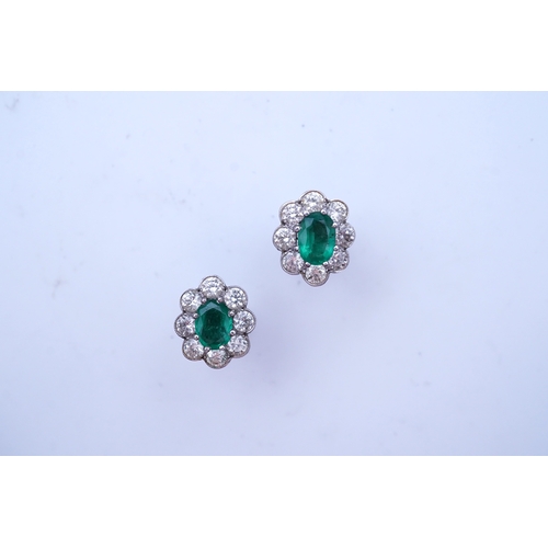 294 - A pair of emerald and diamond earrings, each of cluster design, set with an oval emerald within a mi... 